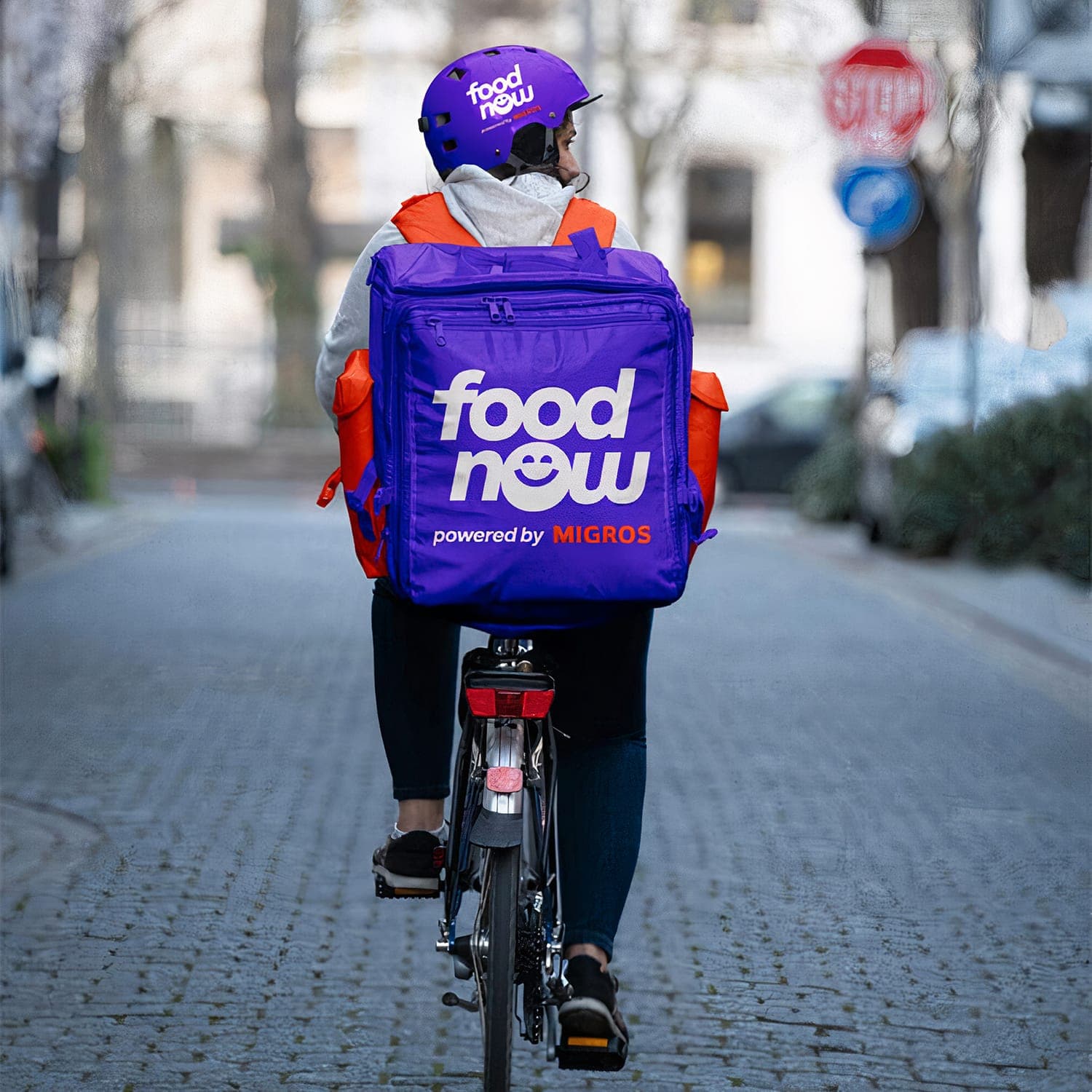 A FoodNow delivery person riding a bike.